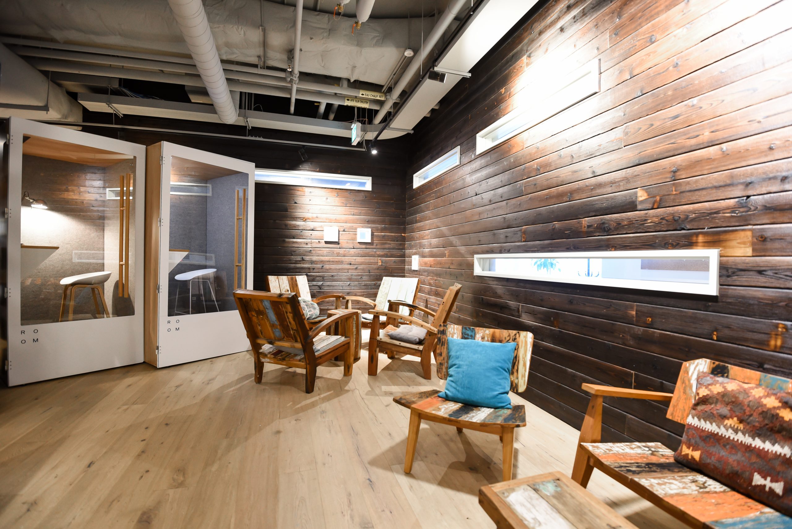 Cozy co-working space with wooden walls, chairs, and private booths.