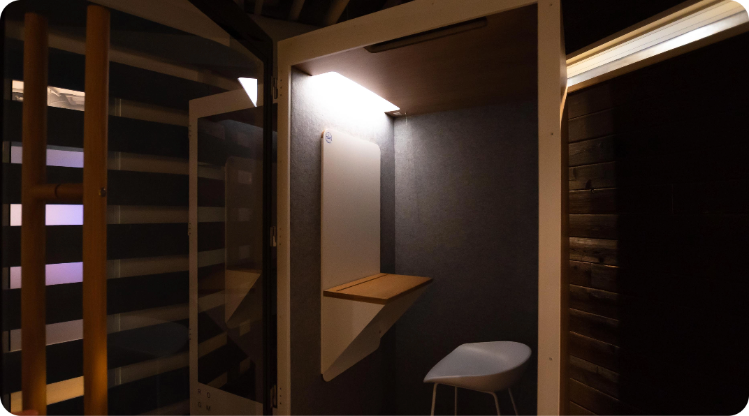 Small, lit private workspace with a chair and shelf.