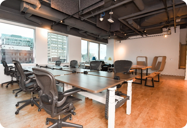 Premium office space with desks, chairs, and large windows showing city buildings.