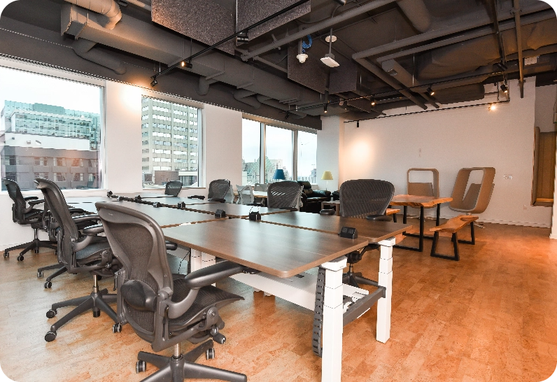 Premium office space with desks, chairs, and large windows showing city buildings.