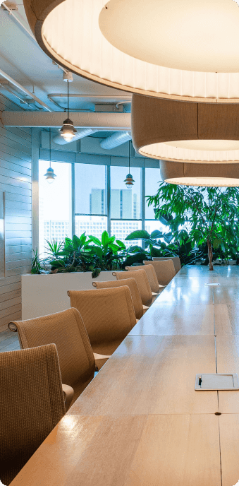 Stylish conference room with a long wooden table, plush chairs, and abundant natural light.