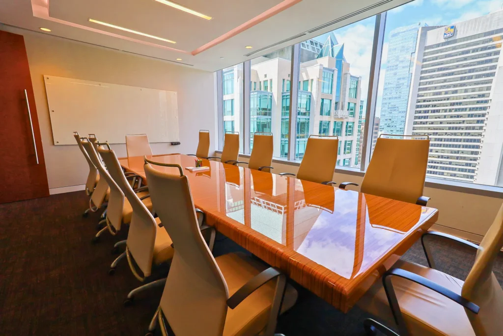 The City Centre offers a spacious meeting room with a large wooden table, several chairs, and a cityscape view through a wide window.