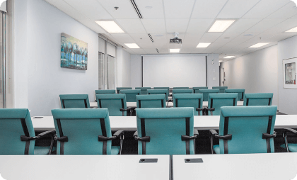 A large meeting room with a big table, chairs, and a big TV on the wall